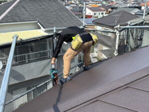 猛暑の屋根上でブロワーを使い雨樋清掃や下地処理を行う塗装職人